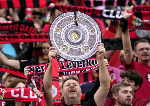 Fanúšik Bayeru Leverkusen drží repliku trofeje.