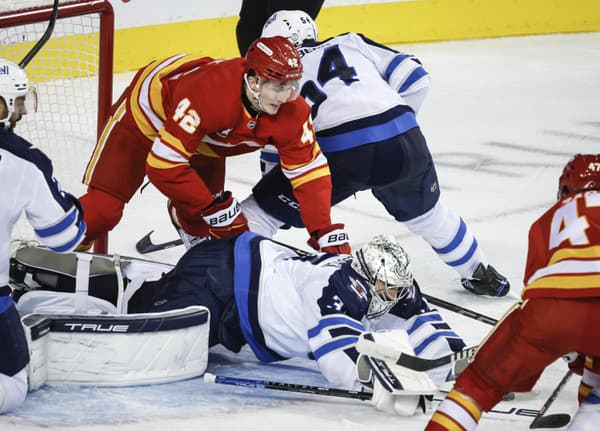 Slovenský hokejista Samuel Honzek (vľavo) z Calgary Flames v súboji pred bránkou.